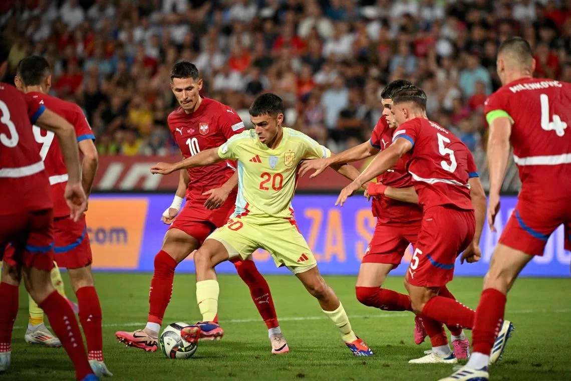 Spain midfielder Pedri (centre) fights for the ball surrounded by Serbia's players.