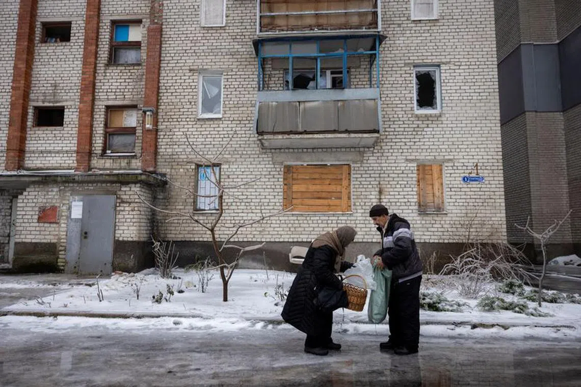 A driver delivers groceries to a woman who is one of the few remaining residents in a neighbourhood that was heavily damaged by fighting in the frontline town of Lyman, amid Russia’s attack on Ukraine, December 15, 2023.  REUTERS/Thomas Peter