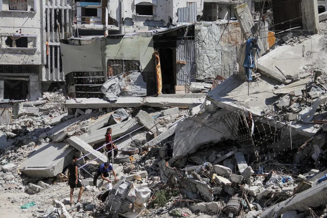 Palestinians walk among the rubble of damaged buildings, which were destroyed during Israel's military offensive, amid the ongoing conflict between Israel and Hamas, in Beit Lahia in the northern Gaza Strip, June 12, 2024. REUTERS/Mahmoud Issa
