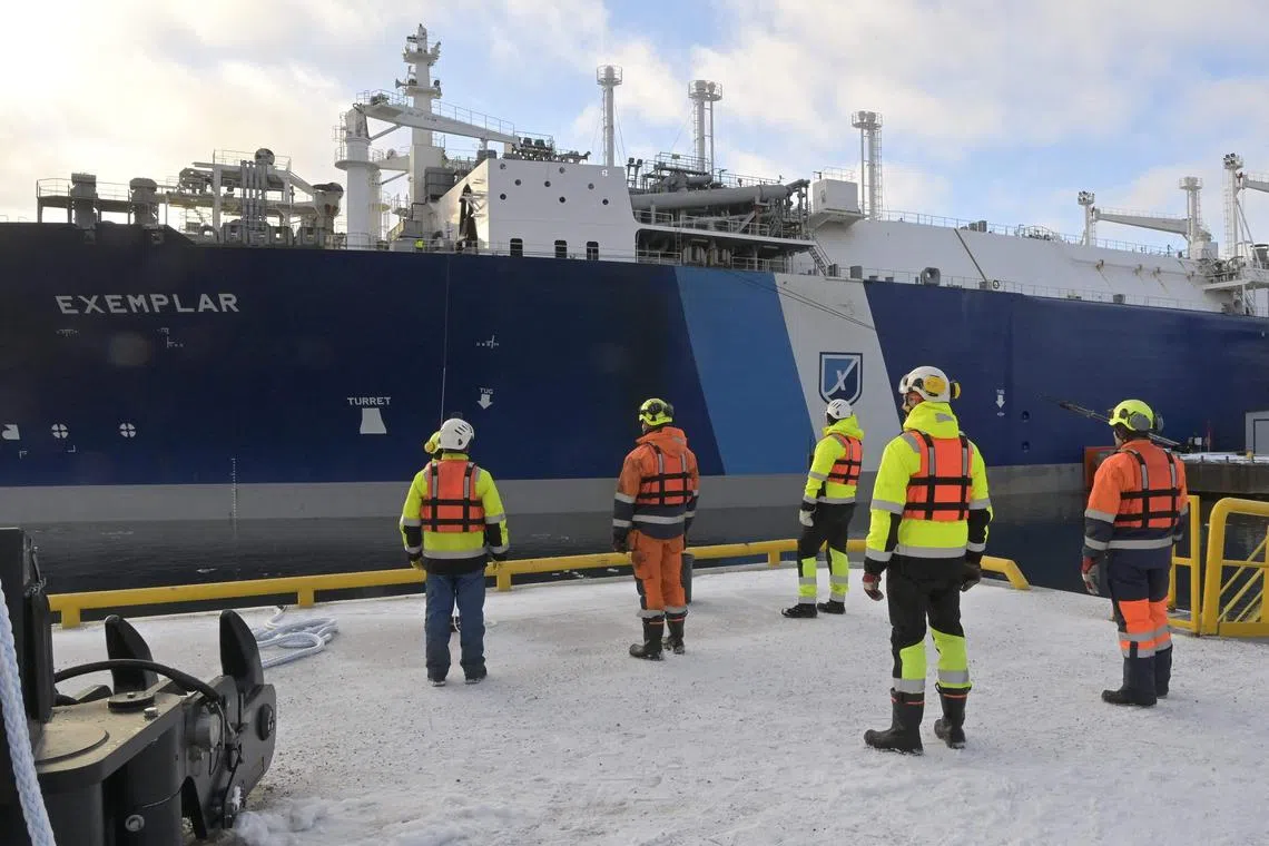 Workers stand in front of the Floating Storage and Regasification Unit (FSRU) ship Exemplar, chartered by Finland to replace Russian gas, at Inkoo port, west of Helsinki, on Dec 30, 2022..