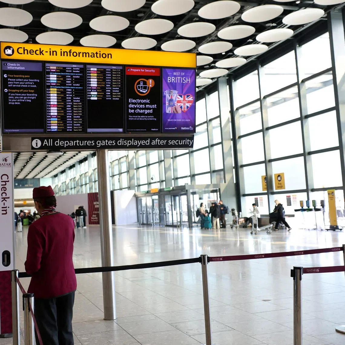 FILE PHOTO: Qatar airline staff stand by a departure board displaying cancelled flights to Middle East countries amid the U.S.-Israel conflict with Iran, at Heathrow Airport Terminal 4, in Greater London, Britain, March 2, 2026. REUTERS/Isabel Infantes/File Photo