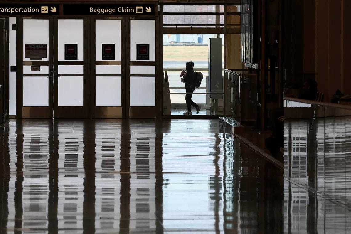 A passenger walks in the terminal at Ronald Reagan Washington National Airport on the busiest travel day of the Thanksgiving holiday, in Arlington, Virginia, U.S., November 25, 2025. REUTERS/Kevin Lamarque