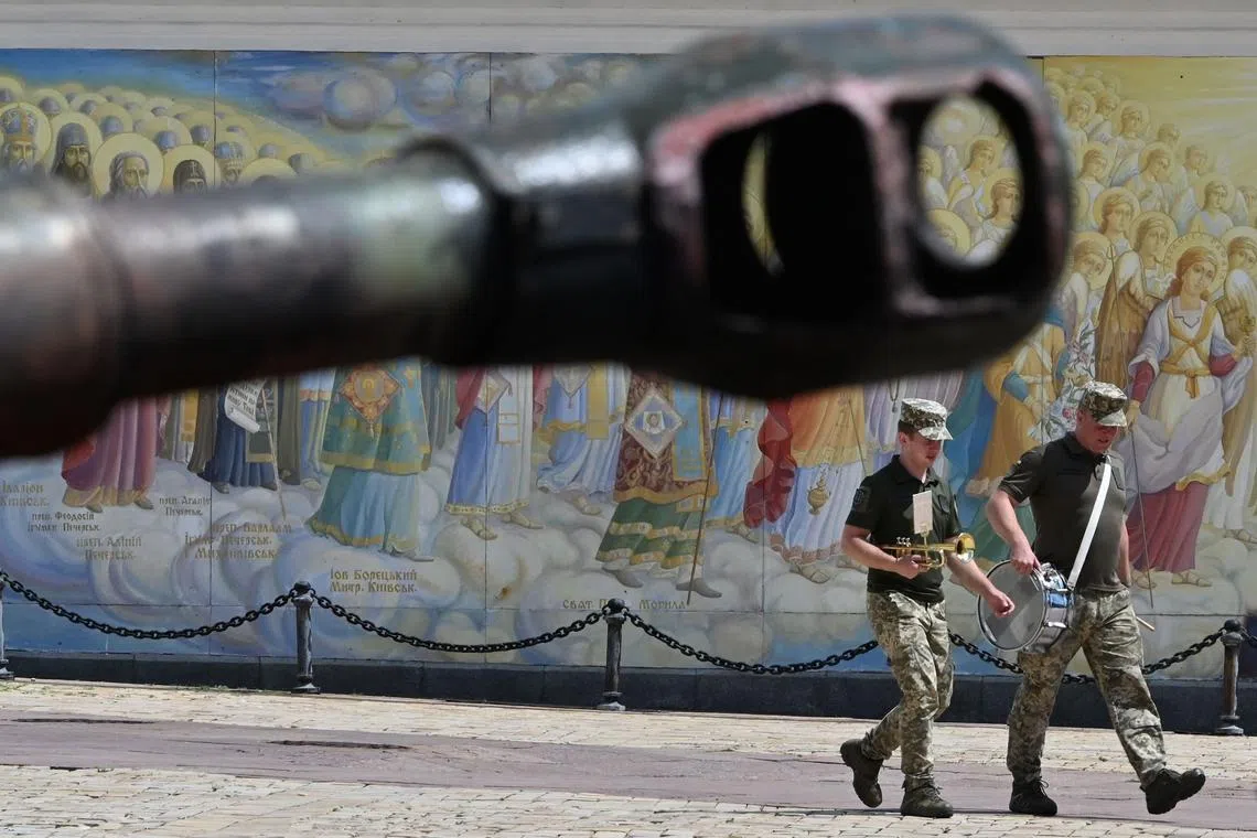 (FILES) Ukrainian servicemen musicians walk past a tank during an open-air exhibition of destroyed Russian military vehicles at Mykhaylo Square in Kyiv, on August 3, 2023, amid the Russian invasion of Ukraine. Saudi Arabia is hosting talks on the Ukraine war on August 5, in the latest flexing of its diplomatic muscle, though expectations are mild for what the gathering might achieve. (Photo by Sergei SUPINSKY / AFP)
