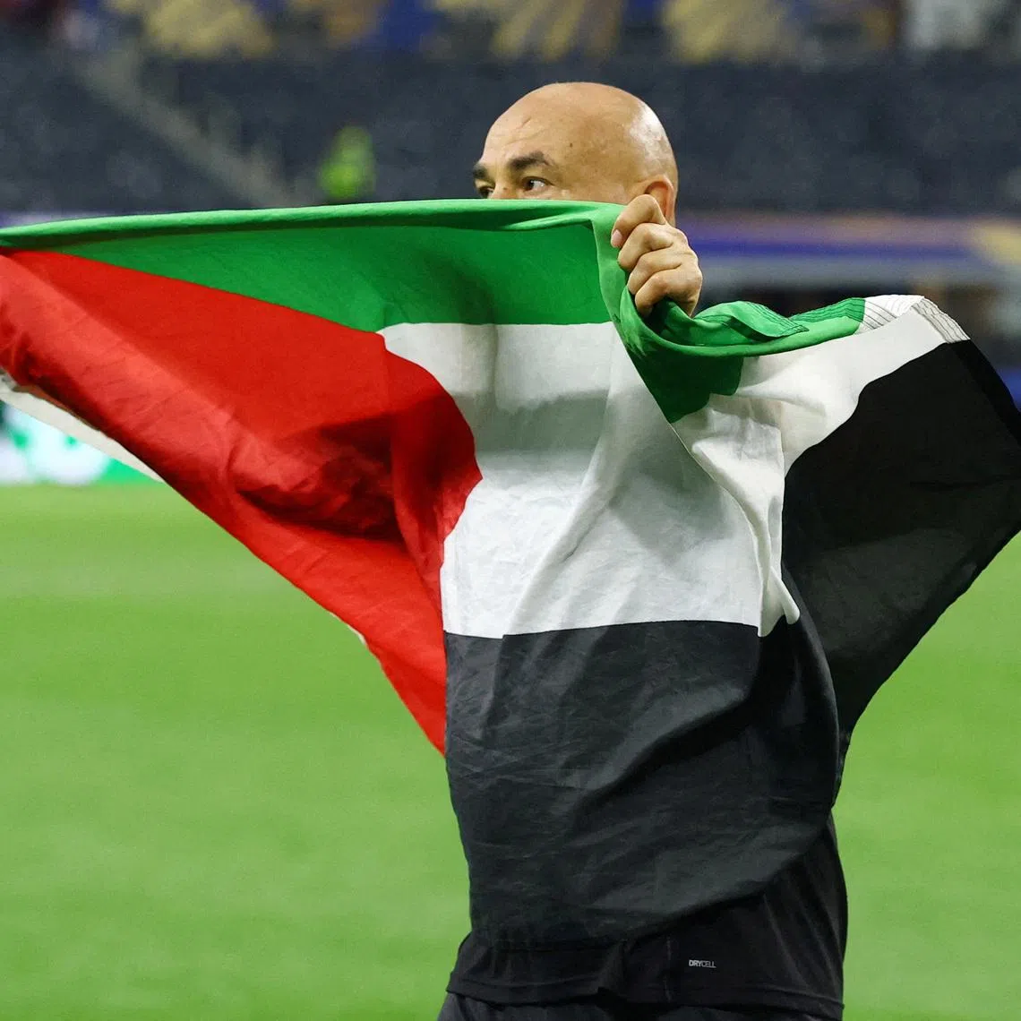 Egypt coach Hossam Hassan celebrates with a Palestine flag after Egypt eliminated Australia in the last 32 in Dallas on July 3.