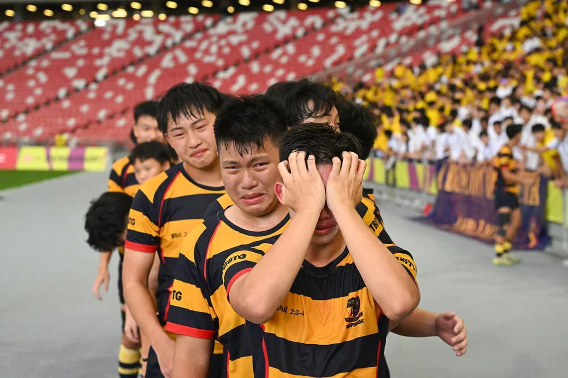 Anglo-Chinese School (Independent)’s B Division rugby captain Jansen Ling holding back his tears alongside emotional teammates before collecting their gold medal at the National Stadium on May 6. They beat St Andrew’s 15-11 in the final to reclaim the title they last won in 2022. ST PHOTO: AZMI ATHNI