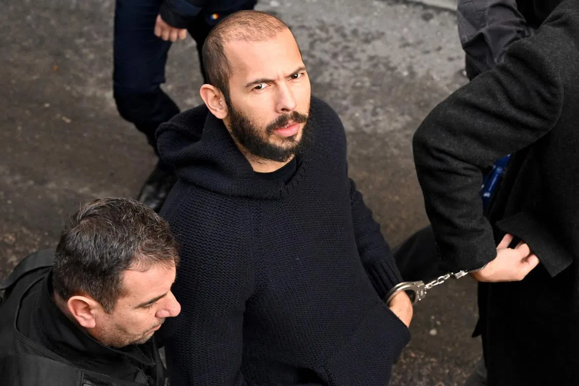 British-US influencer Andrew Tate arrives handcuffed and escorted by police at a courthouse in Bucharest, on Feb 1, 2023.