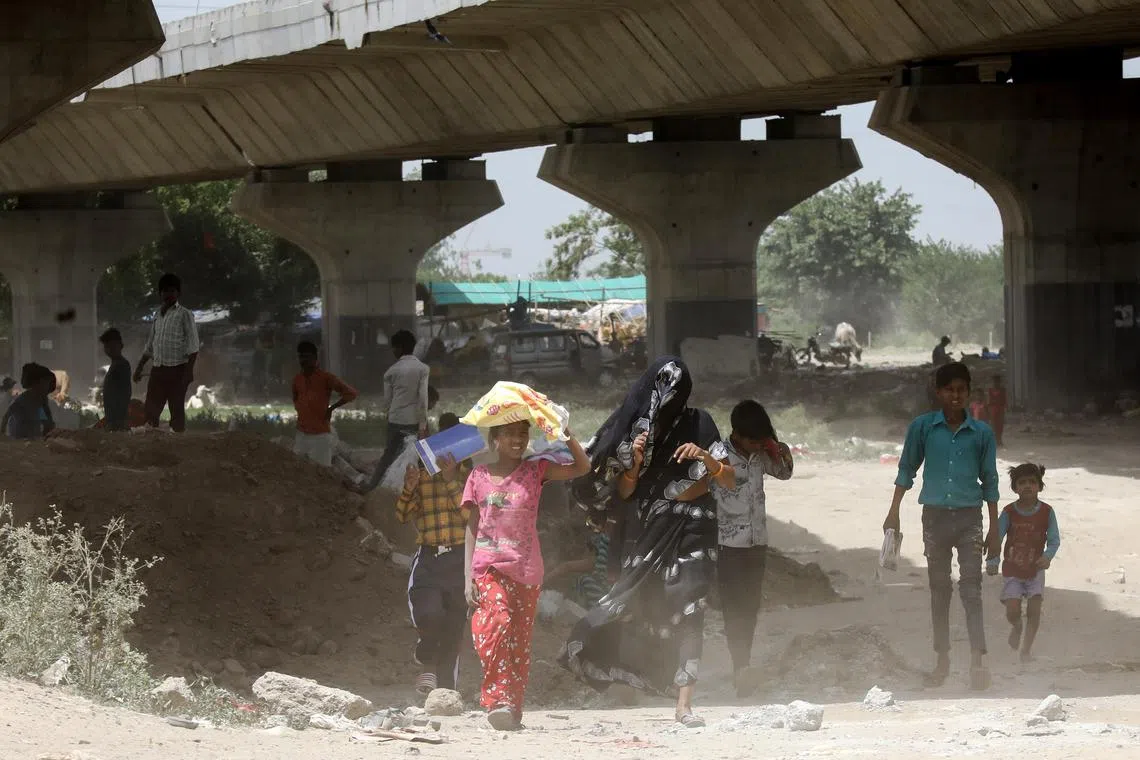 epa10687969 Indian people try to protect themselves from the heat as they walk along the Yamuna riverbed, amidst a heatwave, in New Delhi, India, 13 June 2023. According to the Indian Meteorological Department heatwaves are likely to continue in various parts of India.  EPA-EFE/RAJAT GUPTA