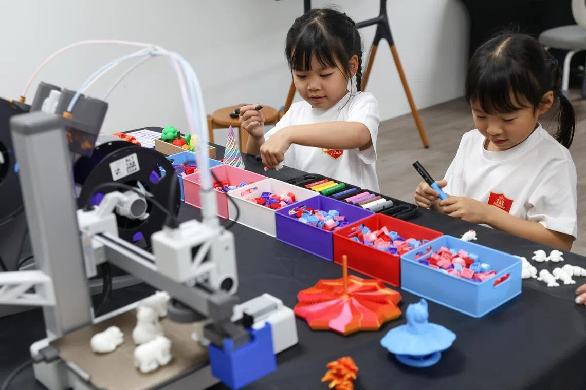 Jayne Low (left) and Mikaela Xie colouring 3-D printed figures at MapleBear Junior Club.