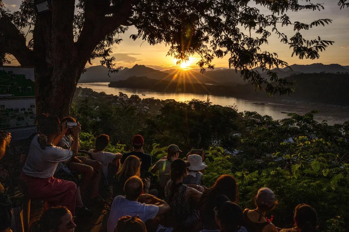 Tourists watch the sunset over the Mekong River in Luang Prabang, Laos, Oct. 22, 2024. The Southeast Asian country has lagged behind Vietnam and Thailand when it comes to tourism but the government hopes new hotels, roads and a train system will put Laos on visitors’ lists. 
