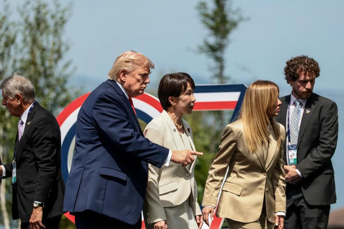 US President Donald Trump gestures next to Japanese Prime Minister Sanae Takaichi and Italian Prime Minister Giorgia Meloni following a group photo during the G-7 summit in Evian-les-Bains.