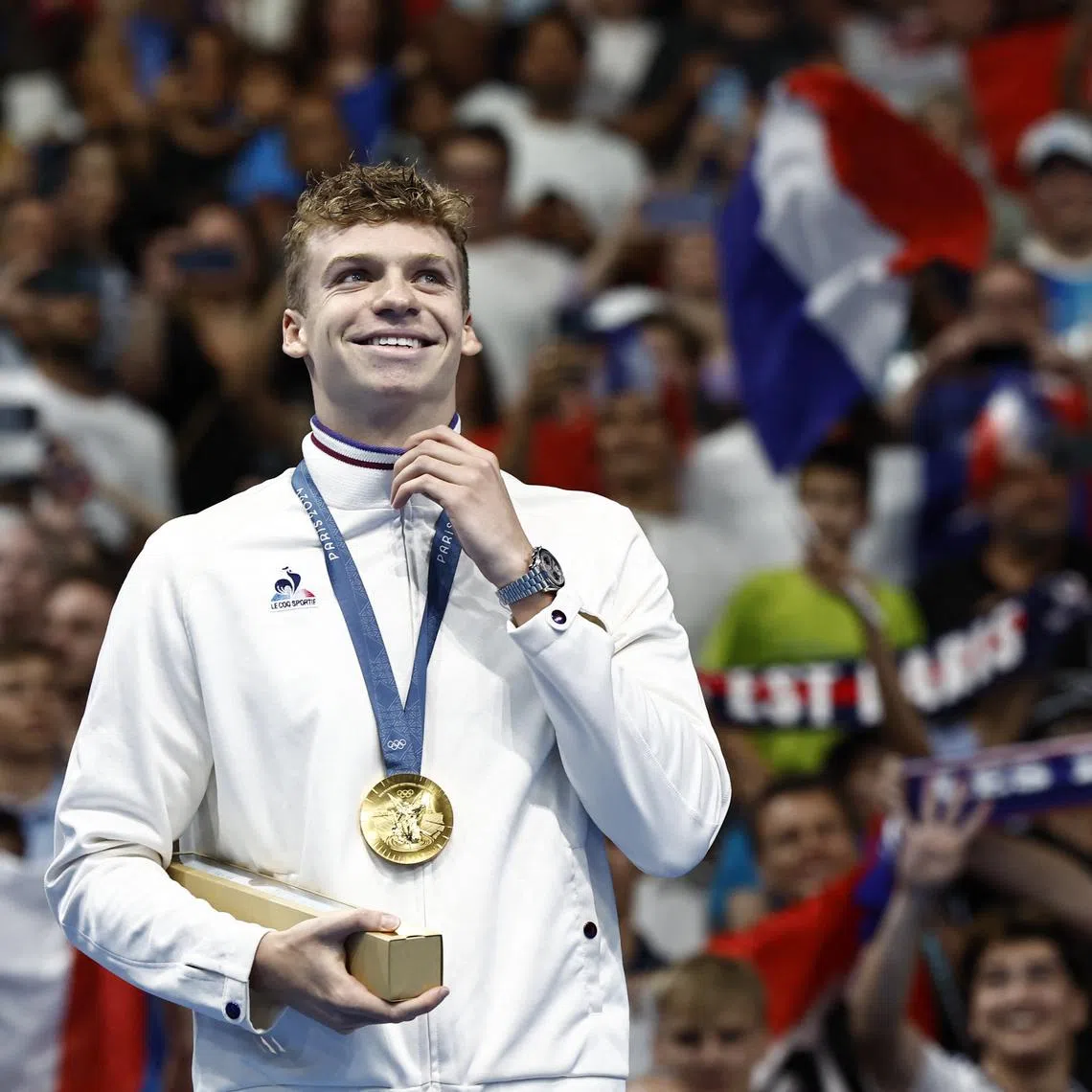 Paris 2024 Olympics - Swimming - Men's 200m Ind. Medley Victory Ceremony - Paris La Defense Arena, Nanterre, France - August 02, 2024. Gold medallist Leon Marchand of France celebrates on the podium after winning gold and setting a new Olympic record. REUTERS/Clodagh Kilcoyne