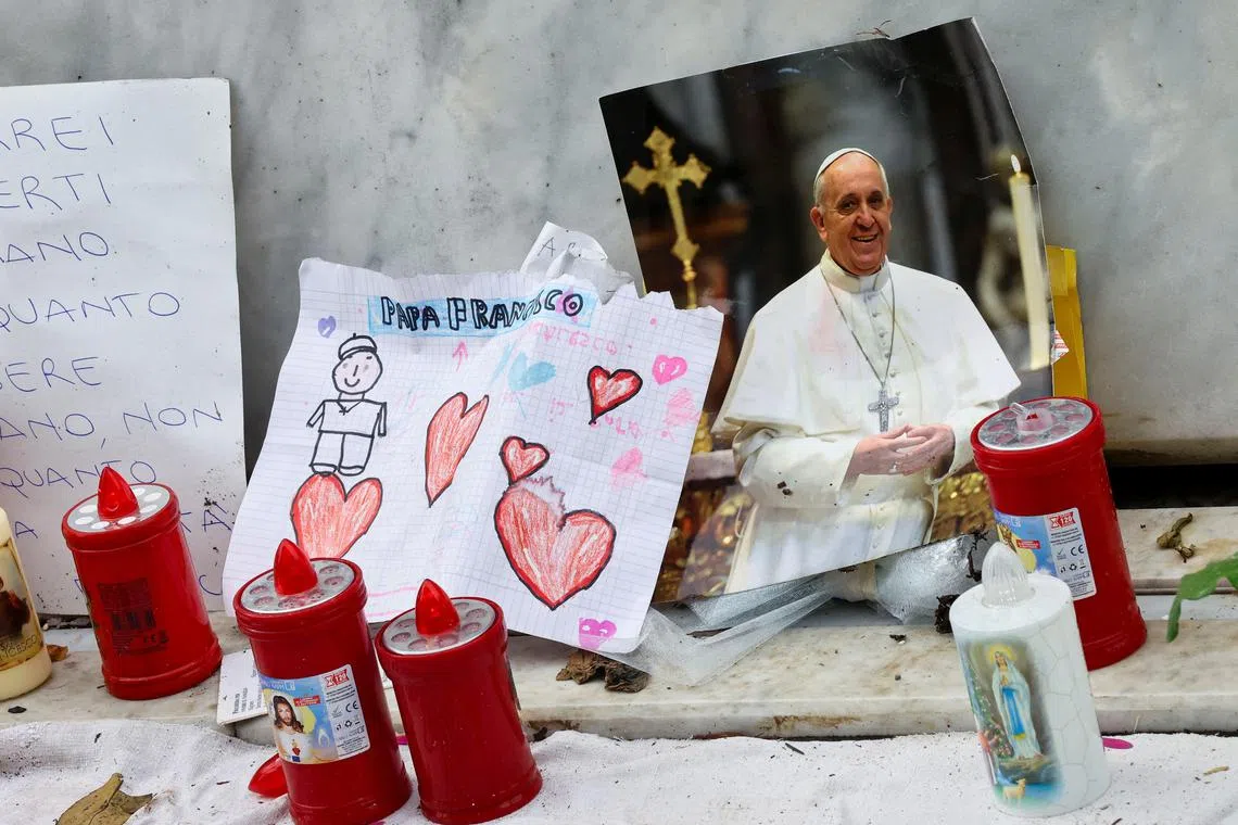 Tributes to Pope Francis are placed at the foot of a statue of the late Pope John Paul II, outside Rome's Gemelli hospital, where the 88-year-old pontiff is undergoing treatment.