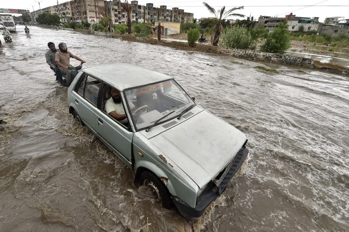 epa11509425 People and vehicles make their way through a water-logged street after heavy rainfall in Karachi, Pakistan, 30 July 2024. The Pakistan Meteorological Department predicted heavy rains from 28 July until 31 July as another monsoon spell hits the country, causing flash flooding and urban flooding in some areas of the country.  EPA-EFE/SHAHZAIB AKBER