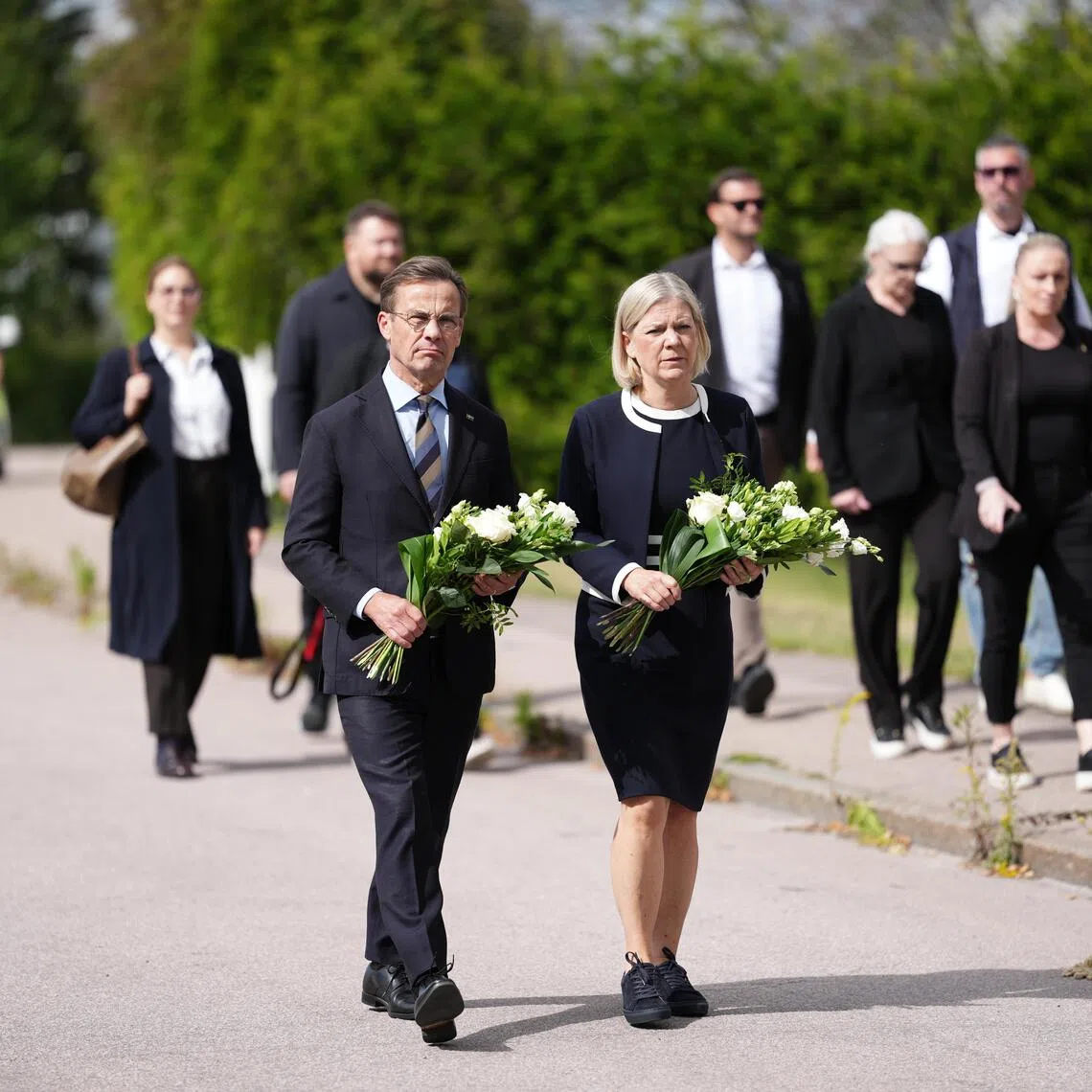Swedish Prime Minister Ulf Kristersson (left) and Social Democratic Party leader Magdalena Andersson visiting the makeshift memorial for a 17-year-old girl who was killed by a man with a sword in Fagersta, Sweden, on Aug 22.