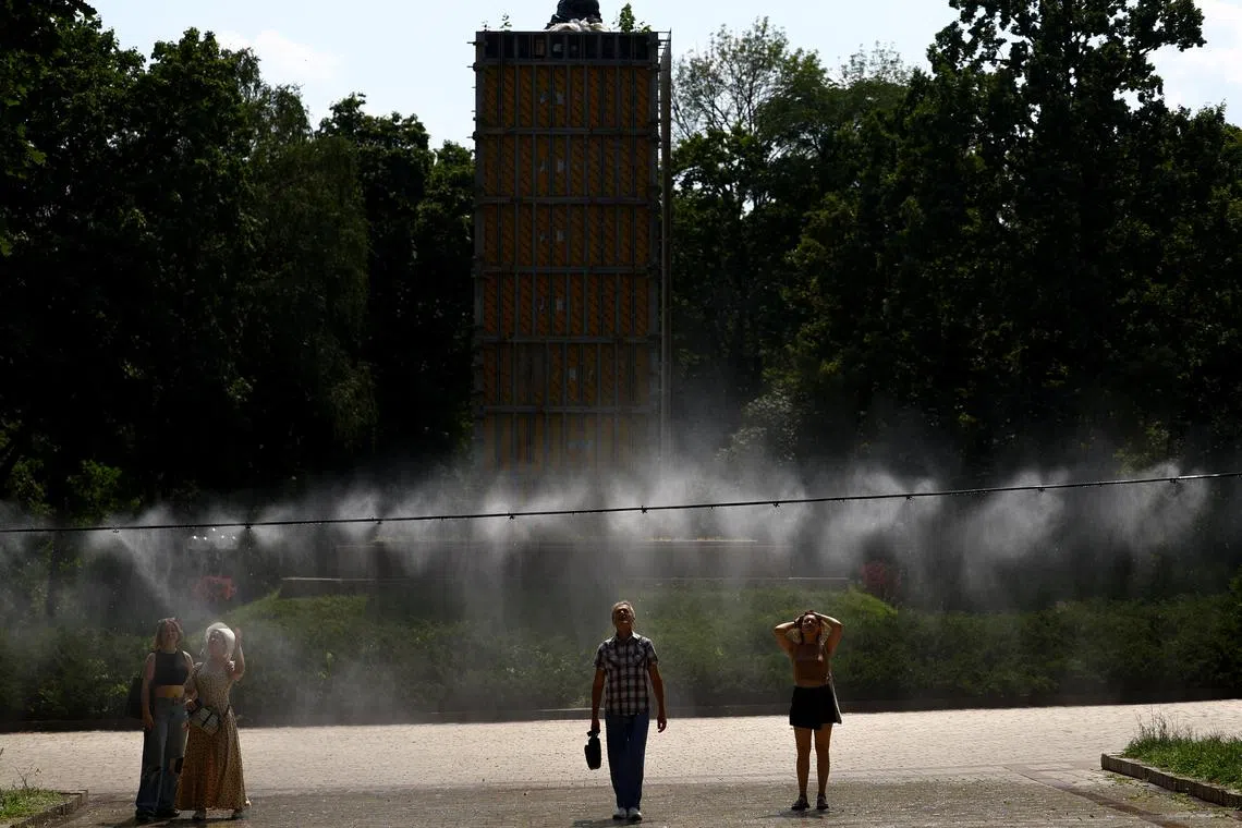 People cool themselves under a water sprinkler on an extremely hot summer day, amid Russia's attack on Ukraine, in a park in central Kyiv, Ukraine July 16, 2024. REUTERS/Valentyn Ogirenko