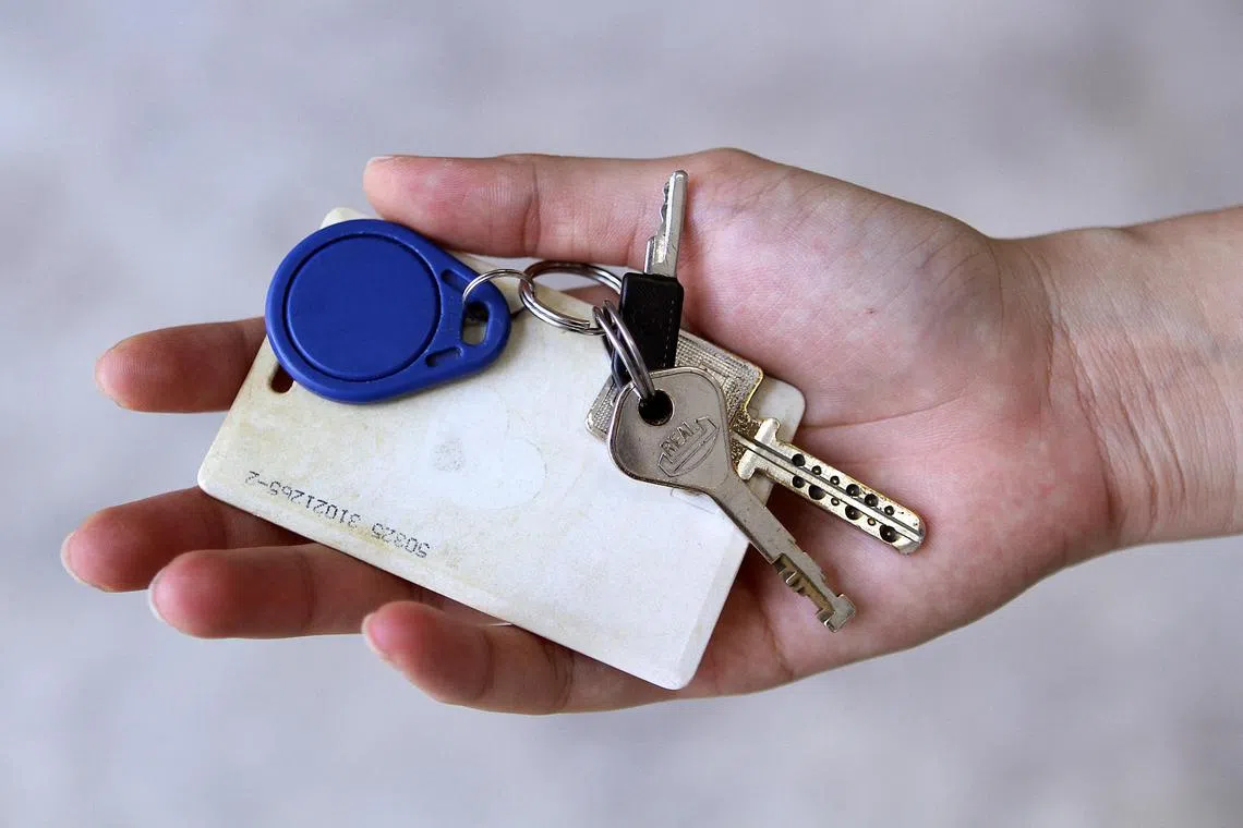 A door access card and some keys on the palm of a hand.
