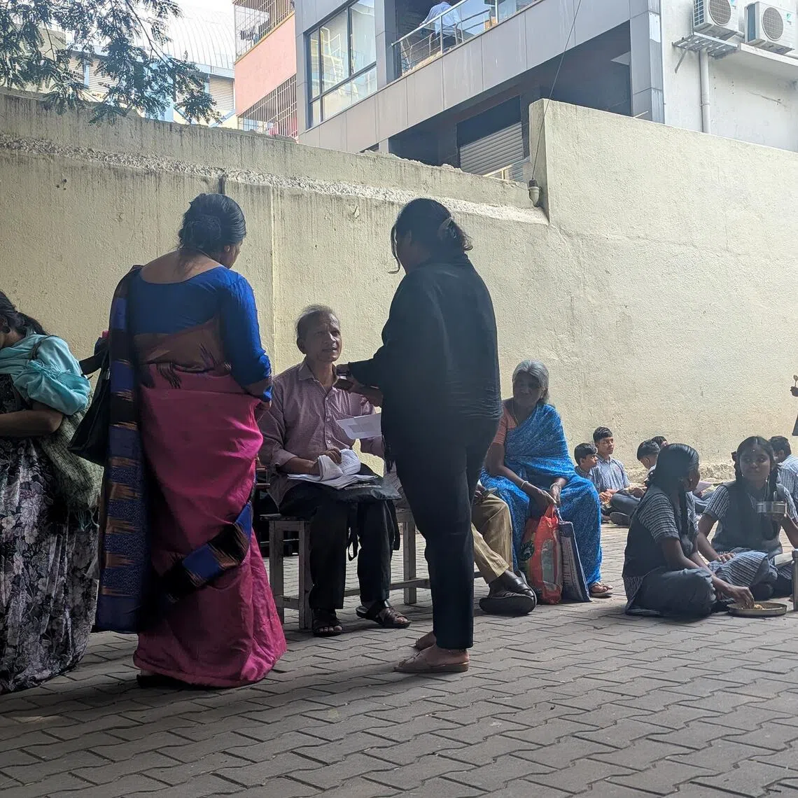 Voters whose names have been flagged for deletion under the Special Intensive Revision in India wait at a Bengaluru school to get their identification documents verified by election officials.