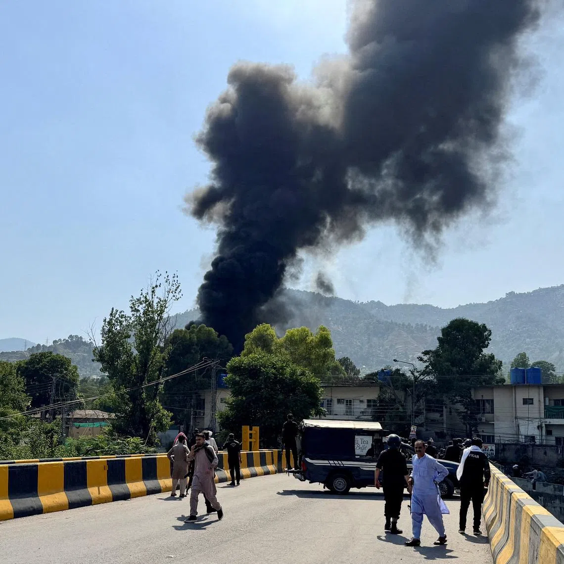 People and police gather nearby as smoke billows from the site where an Mi-17 helicopter of Pakistan Army Aviation crashed near Muzaffarabad, Pakistani Kashmir, June 10, 2026. Picture taken with a mobile phone. REUTERS/Tariq Maqbool