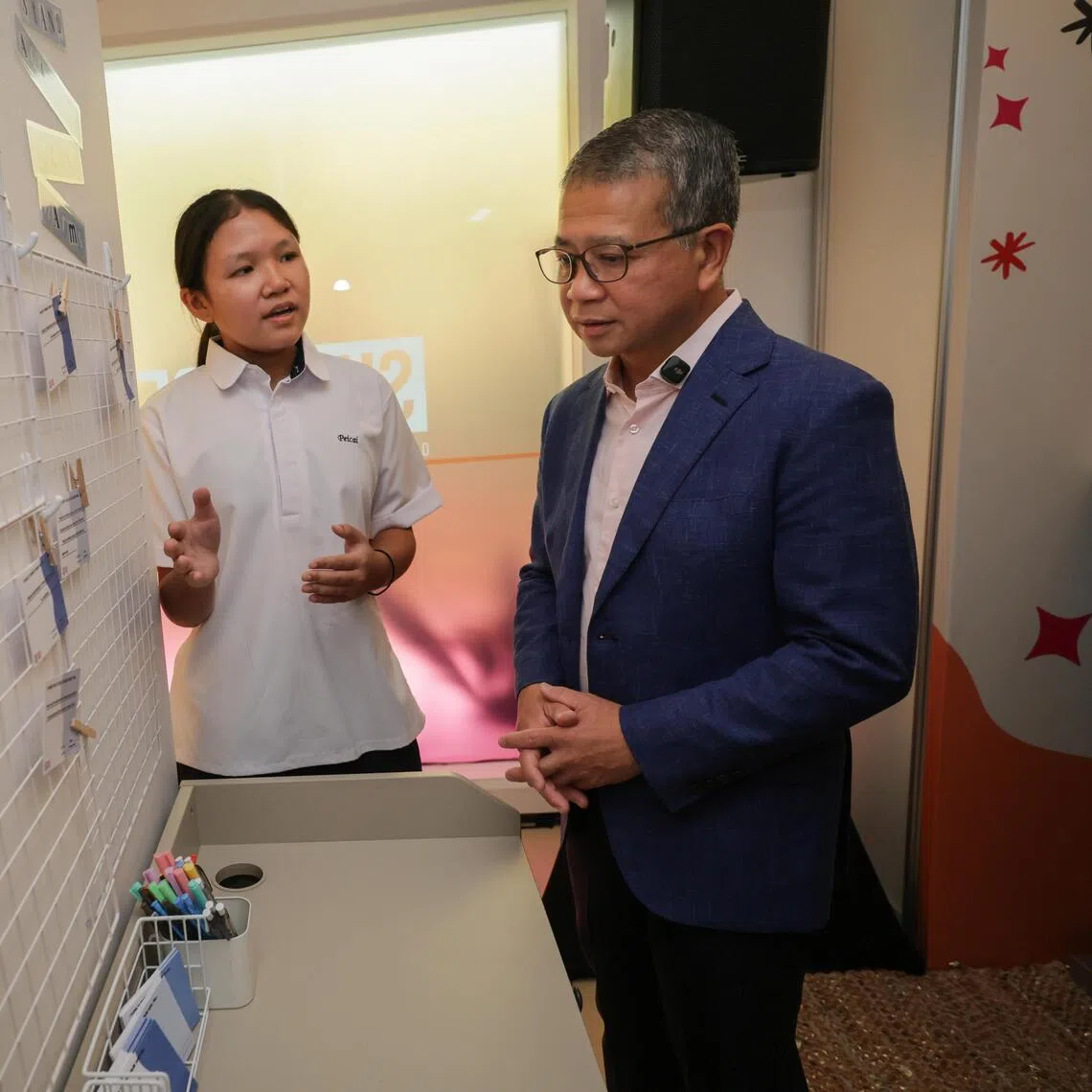 Starlett Seng, a secondary two student from Peicai Secondary School, introducing Minister for Law Edwin Tong to an interactive display aimed at raising awareness of how individuals can stand against online harms, at the SHECARES Centre on July 24.