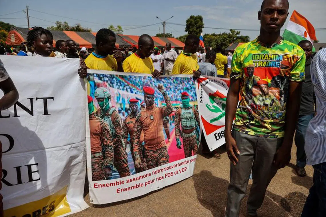 Supporters of Burkina Faso's junta hold a banner with a picture of Captain Ibrahim Traore while attending a rally to mark the one-year anniversary of the coup that brought Traore to power in Ouagadougou, Burkina Faso September 29, 2023.REUTERS/ Yempabou Ouoba