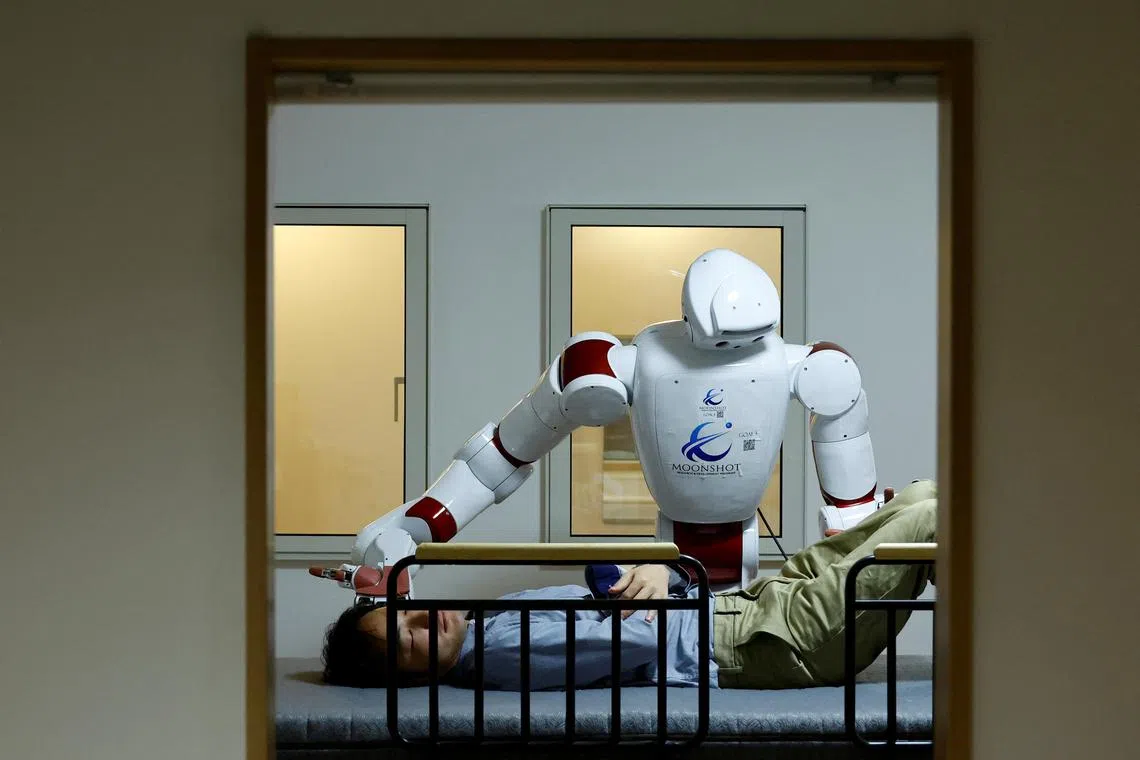 Airec, an artificial intelligence-driven humanoid robot, demonstrates a manoeuvre for changing diapers or preventing bedsores with a researcher at Waseda University's laboratory in Tokyo, Japan. 