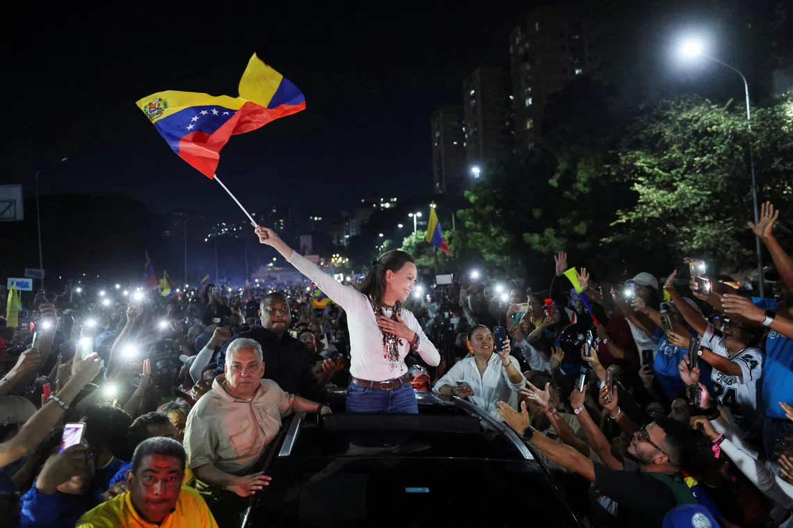 Venezuelan opposition leader Maria Corina Machado waves a Venezuela flag while greeting supporters as she arrives in Caracas after travelling by road from Barquisimeto, where she made her first public appearance following her return to the country after nearly a year abroad, in Caracas, Venezuela, October 25, 2026. REUTERS/Leonardo Fernandez Viloria