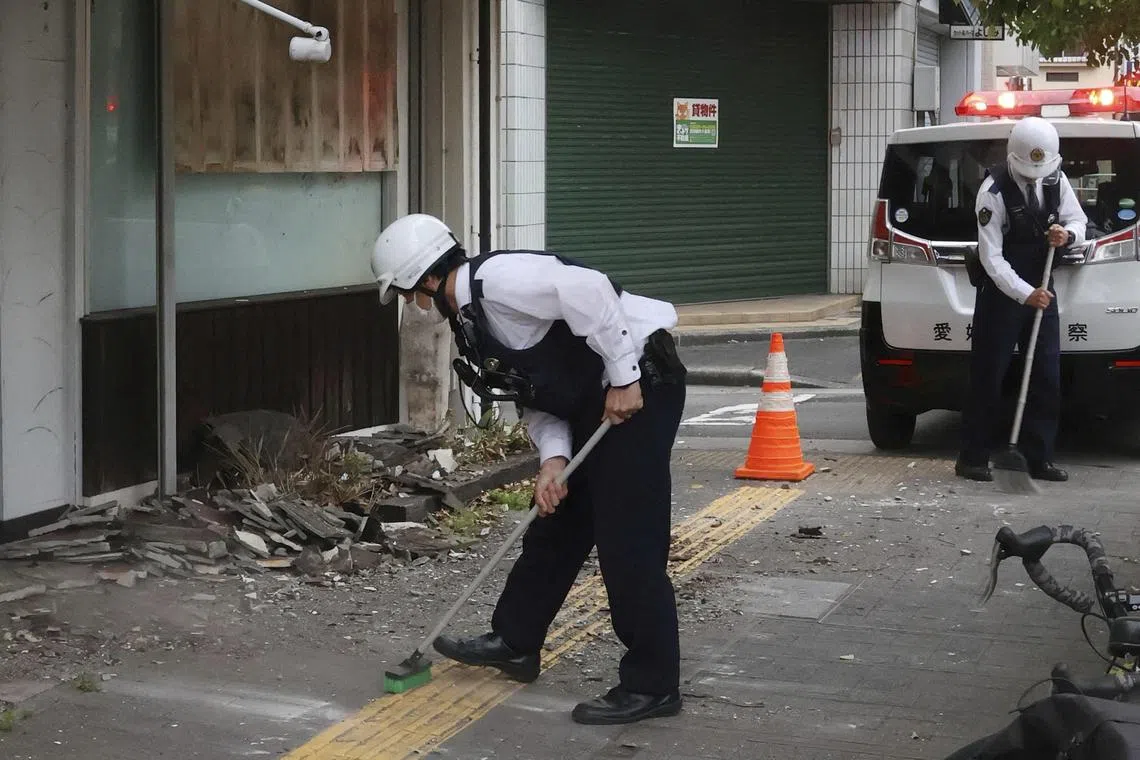 Police officers try to remove debris caused by an earthquake in Uwajima, Ehime prefecture, western Japan April 18, 2024. 