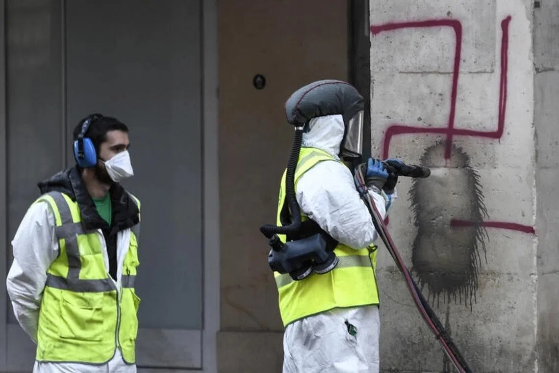 A 2020 photo shows municipal workers clearing a swastika sign spray-painted in Paris. 