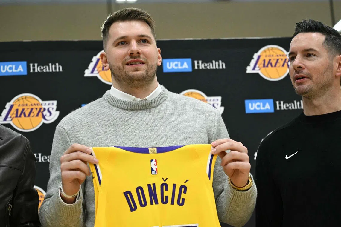 Slovenian basketball player Luka Doncic (left) holds up a jersey as he stands alongside Los Angeles Lakers head coach JJ Redick.
