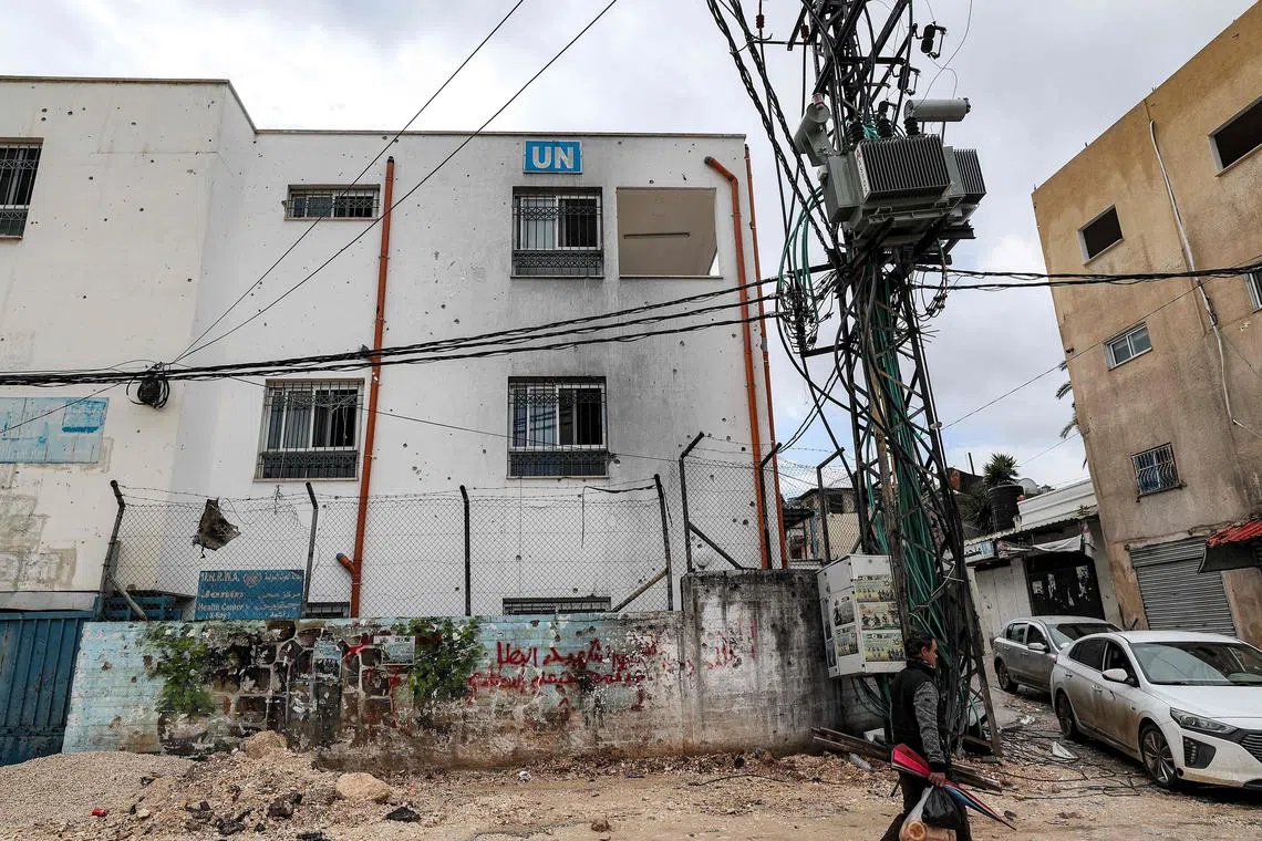 A man walks past a facility of the United Nations Relief and Works Agency for Palestine Refugees in the Near East (UNRWA) in the city of Jenin in the occupied West Bank on January 30, 2024. At least 12 countries -- with top donors the United States and Germany joined by New Zealand on January 30 -- have suspended their funding to UNRWA over Israeli claims that some of its staff members were involved in the October 7 attack. (Photo by Jaafar ASHTIYEH / AFP)