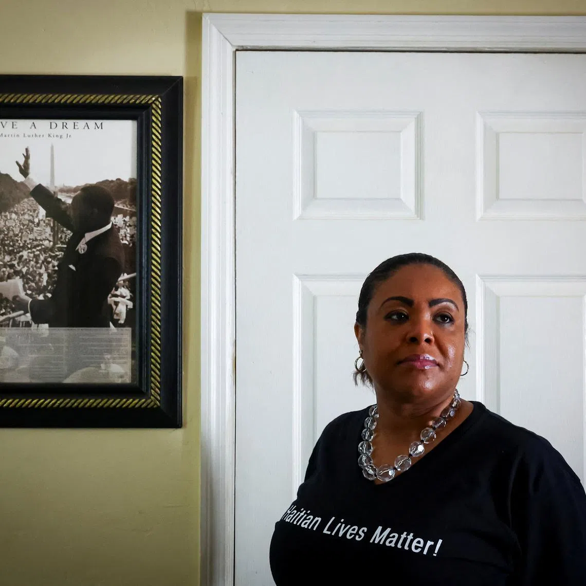 Farah Larrieux, a Temporary Protected Status (TPS) holder, poses for a portrait next to a Martin Luther King Jr. poster during an interview with Reuters, in Miami, Florida, U.S., June 28, 2026. REUTERS/Marco Bello