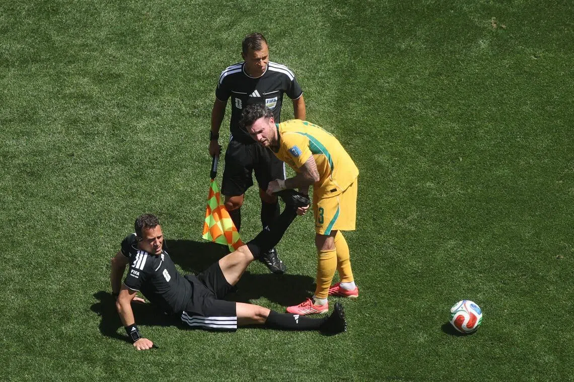 SEATTLE, WASHINGTON - JUNE 19: Referee Felix Zwayer is helped stretching his leg by Aiden O'Neill #13 of Australia after cramping during the FIFA World Cup 2026 Group D match between USA and Australia at Seattle Stadium on June 19, 2026 in Seattle, Washington.   Alex Grimm/Getty Images/AFP (Photo by ALEX GRIMM / GETTY IMAGES NORTH AMERICA / Getty Images via AFP)