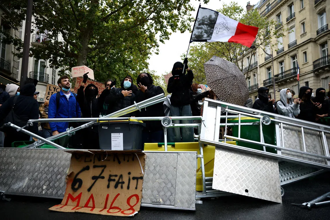 A protester holds a French flag behind a barricade to block the Boulevard Saint-Germain during a blockade of Sciences Po university in Paris as part of nationwide student protests demanding better school conditions, France, October 7, 2026. The slogan on the placard reads \"\"Generation Six - Seven re-enacts May 68\".  REUTERS/Sarah Meyssonnier