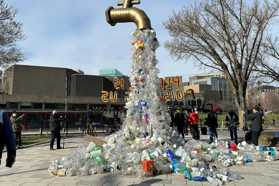 A prop depicting a water tap with cascading plastic bottles is displayed near the venue for a plastics treaty in Canada.