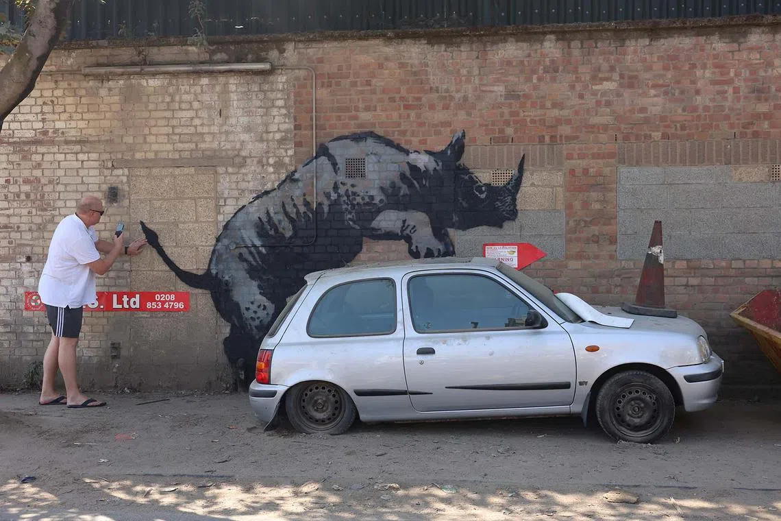 A person taking a photo of a new artwork by the British artist Banksy in Charlton, London, Britain, Aug 12, 2024.