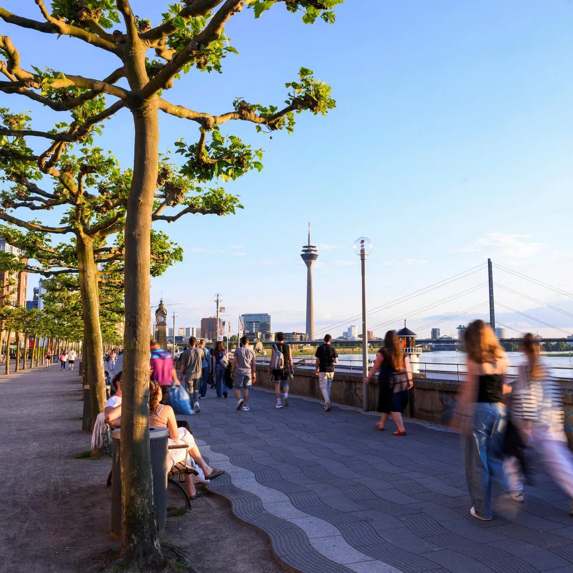 FILE PHOTO: People walk at the promenade by the river Rhine with the skyline in the background including the Rheinturm in Duesseldorf, Germany, May 13, 2024. Picture taken with long exposure. REUTERS/Jana Rodenbusch/ File Photo