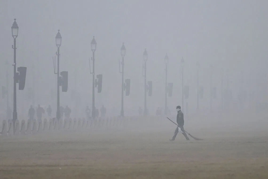 A civic worker covering his face as he walks along the Kartavya Path amid heavy smog in New Delhi, on Dec 18, 2025.