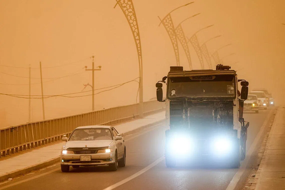 Motorists driving their vehicles through low visibility conditions as a massive dust storm advances on Nasiriyah in Iraq's southern Dhi Qar province on April 14, 2025. Around 1,500 people were sent to hospitals with respiratory problems on April 14 as a storm hit central and southern Iraq, health officials said. 
