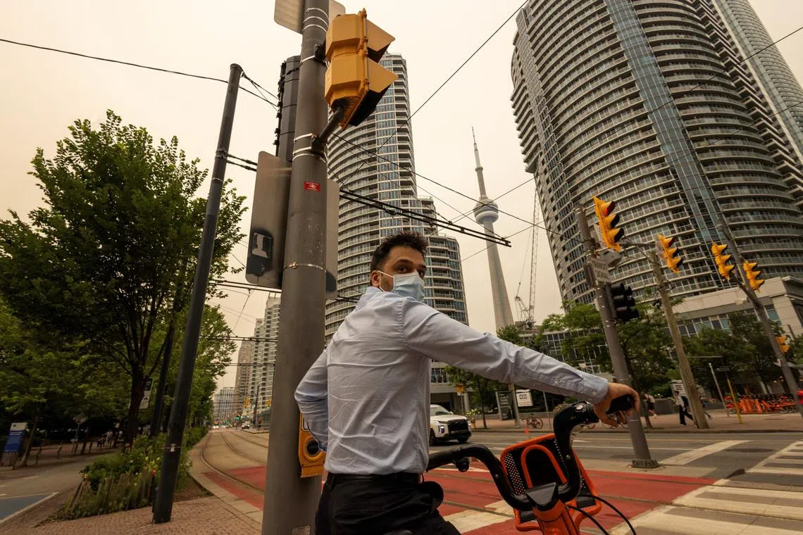 A man wears a mask as wildfire smoke from northwestern Ontario fills the sky, prompting health warnings and calls for residents to limit outdoor activity.