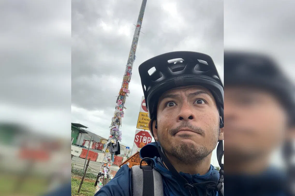 Film-maker M. Raihan Halim on his weekend bike ride and next to the sticker-covered landmark, Tuas Lamp Post 1. 