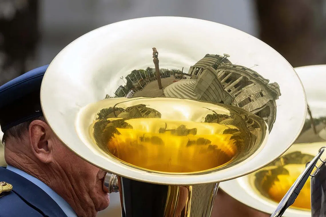 TOPSHOT - The parliament building is reflected in a tuba played by a military honour guard during the re-starting of Parliament following the October 14 general election, in Wellington on December 6, 2023. (Photo by Marty MELVILLE / AFP)
