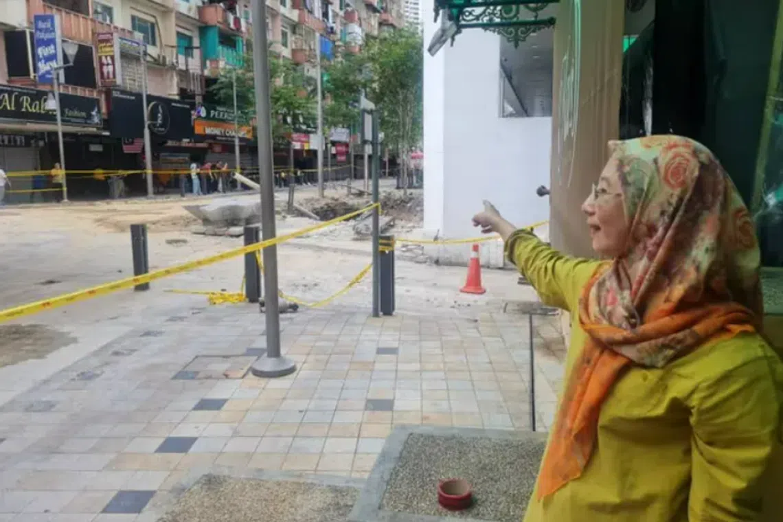 Ms Asmawati points towards the sinkhole, which is 15m away from her clothing shop. 