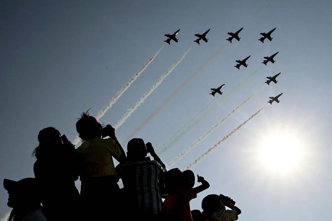 Children watching the Indian Air Force (IAF) Surya Kiran aerobatics team performing during Aero India 2025, a military aviation exhibition at the Yelahanka Air Force Station in Bengaluru on Feb 13, 2025. 