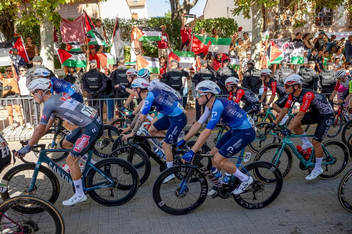 Demonstrators, some holding Palestinian flags, protest as some Israel-Premier Tech team riders pass during the 21st and final stage of La Vuelta a Espana cycling race on Sept 14, 2025.