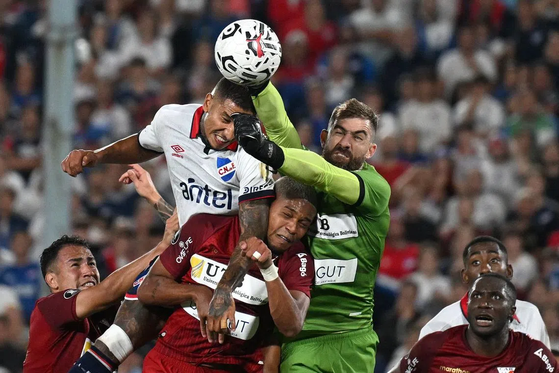 Nacional's defender Juan Manuel Izquierdo (centre) and Always Ready's goalkeeper Alain Baroja vying for the ball during the Copa Libertadores football match at the Gran Parque Central stadium in Montevideo, on March 14, 2024. 