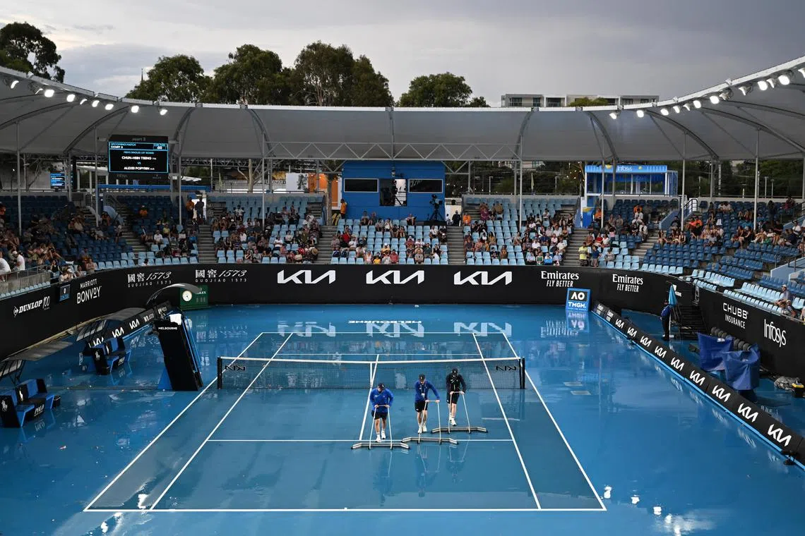 Attendants sweep off the rain during the first round of the 2023 Australian Open tennis tournament on Jan 17, 2023. 