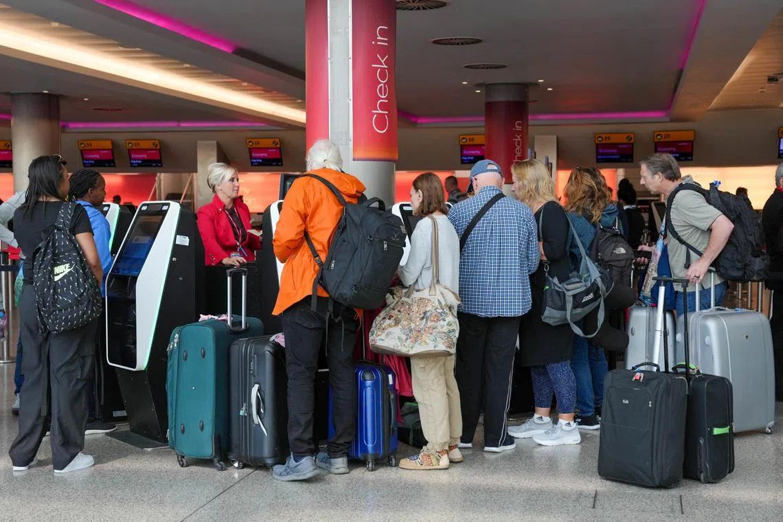 FILE PHOTO: Passengers queue for the assistance with self check-in machines at Heathrow Terminal 3 in London, Britain, August 22, 2023. REUTERS/Maja Smiejkowska/ File Photo