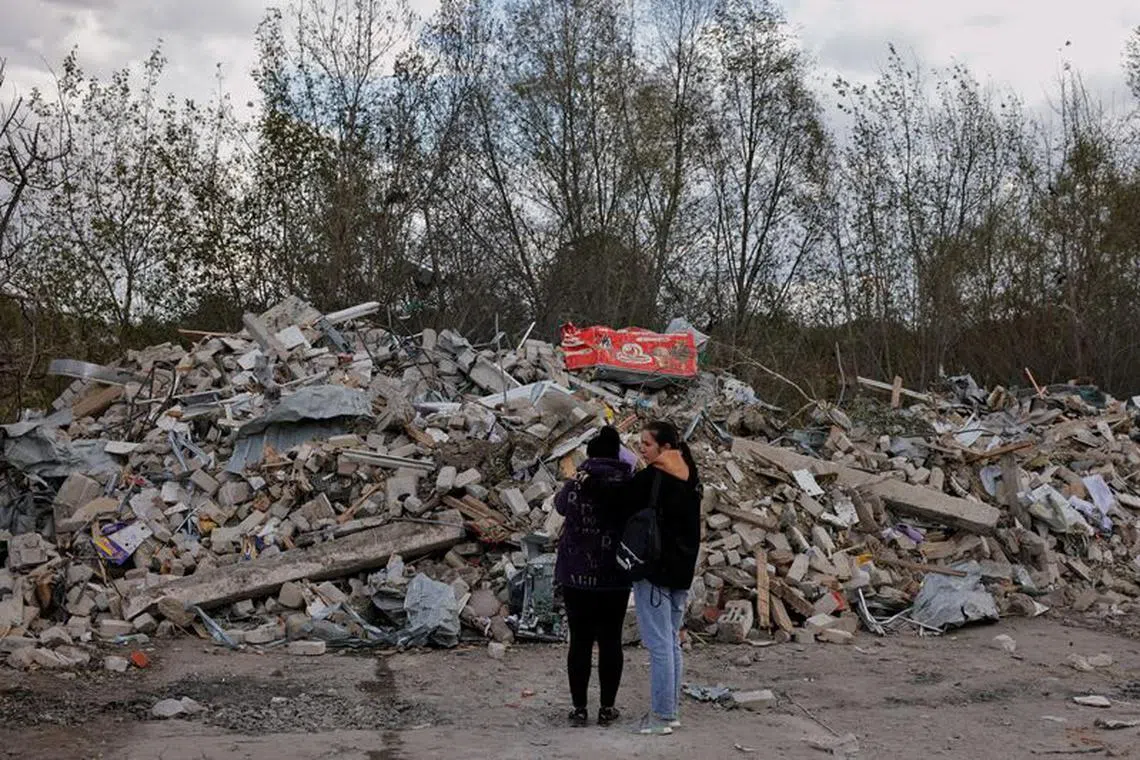 FILE PHOTO: Two women react in front of a pile of rubble that is left of the cafe that hosted the wake and was hit by a Russian missile, following a Russian military strike, amid Russia's attack on Ukraine, in the village of Hroza, Kharkiv region, Ukraine October 6, 2023. REUTERS/Thomas Peter/File photo