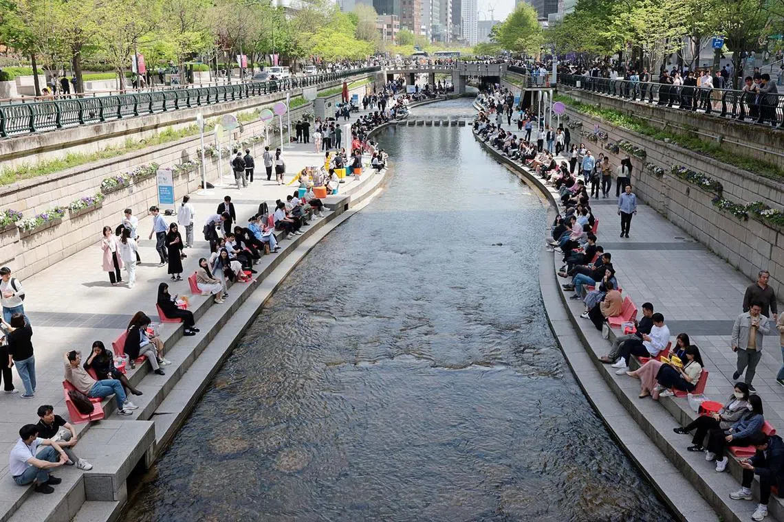 People reading books at an outdoor library, which opened along the Cheonggye Stream in downtown Seoul, South Korea, April 18, 2024. 