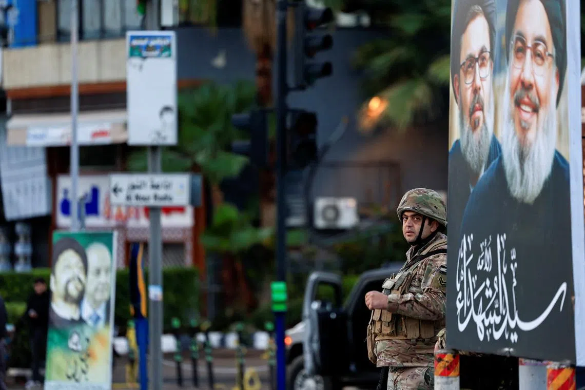 A soldier stands guard next to a poster with the images of late Hezbollah leader Sayyed Hassan Nasrallah and late senior Hezbollah official Hashem Safieddine, at the entrance of Beirut's southern suburbs, after a ceasefire between Israel and Iran-backed group Hezbollah took effect at 0200 GMT on Wednesday after U.S. President Joe Biden said both sides accepted an agreement brokered by the United States and France, in Lebanon, November 27, 2024. REUTERS/Thaier Al-Sudani